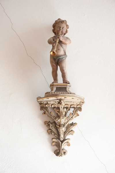 Putto making music on pedestal